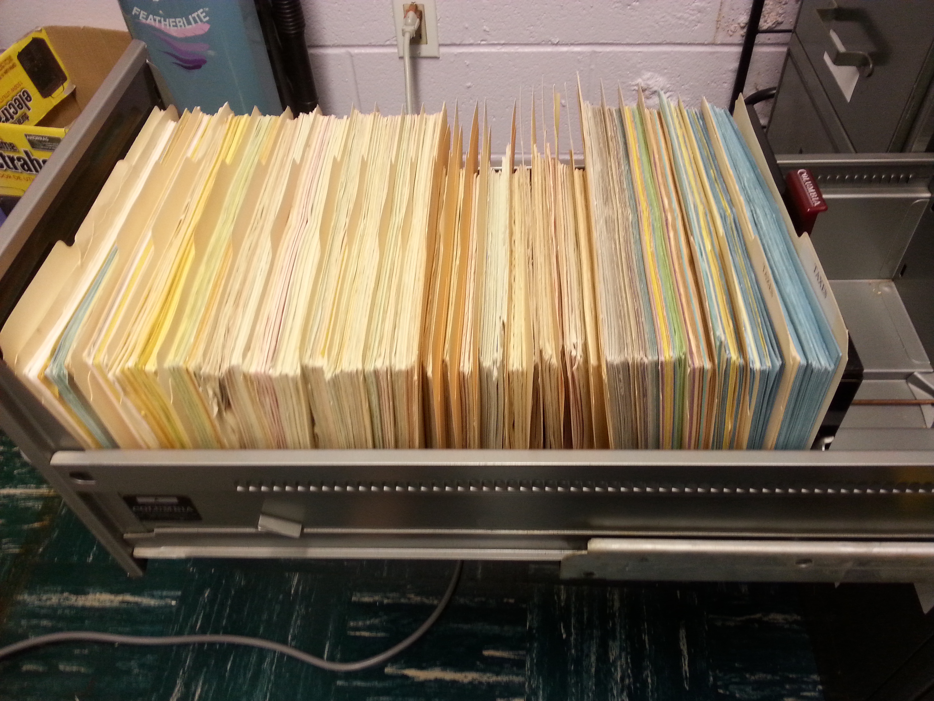 Photograph of metal file cabinet drawer pulled out to reveal 2.5 feet of a multi-colored newsletter placed neatly in manila folders.