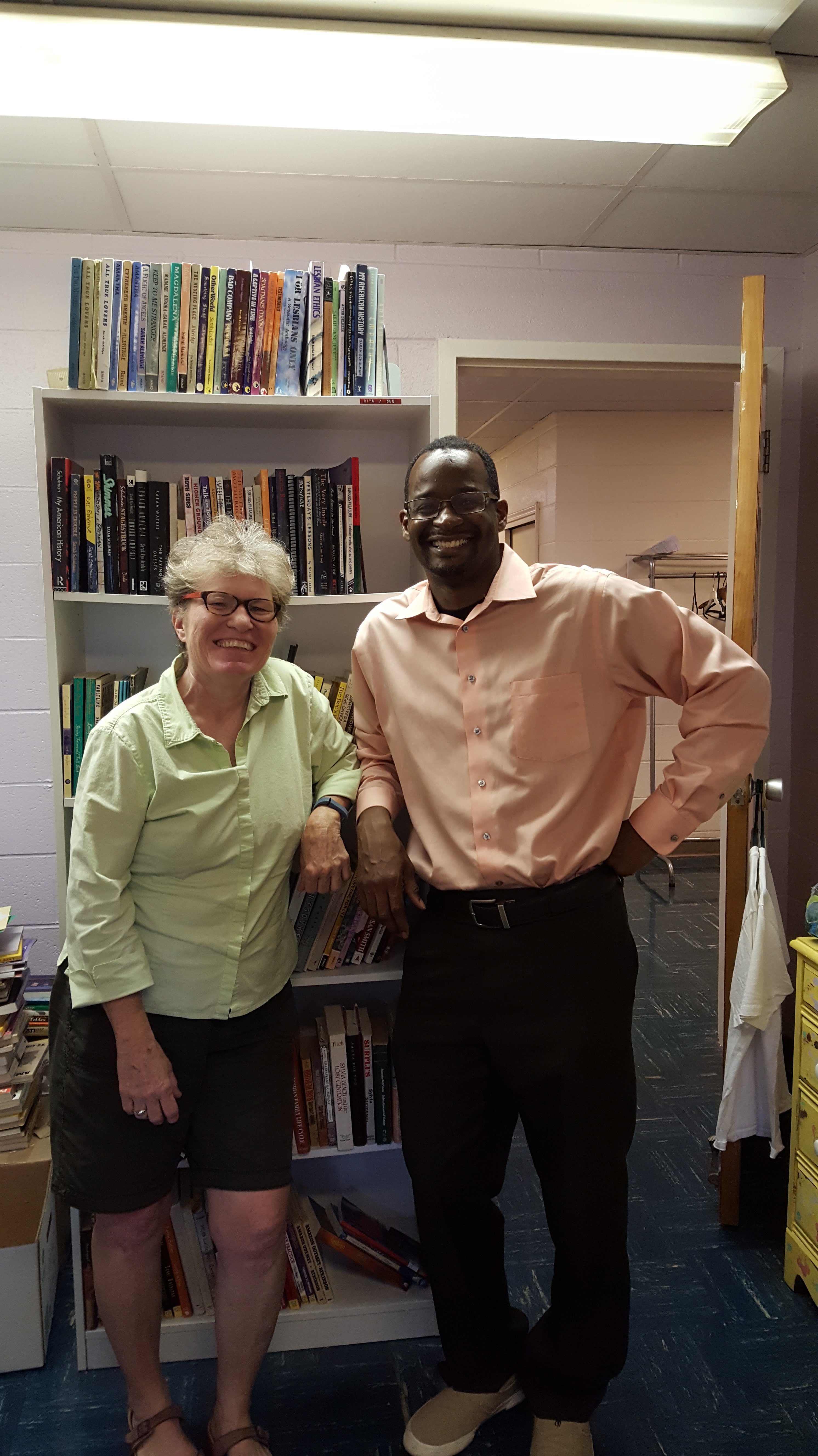 Phebe and Anthony stand next to each other leaning against the shelves